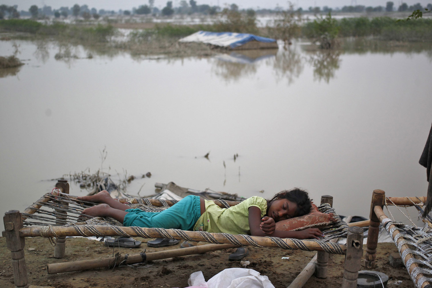 June 21, 2013. A displaced girl sleeps outside her makeshift tent at a camp by the roadside after a rise in the waters of the river Yamuna after heavy rains in New Delhi.