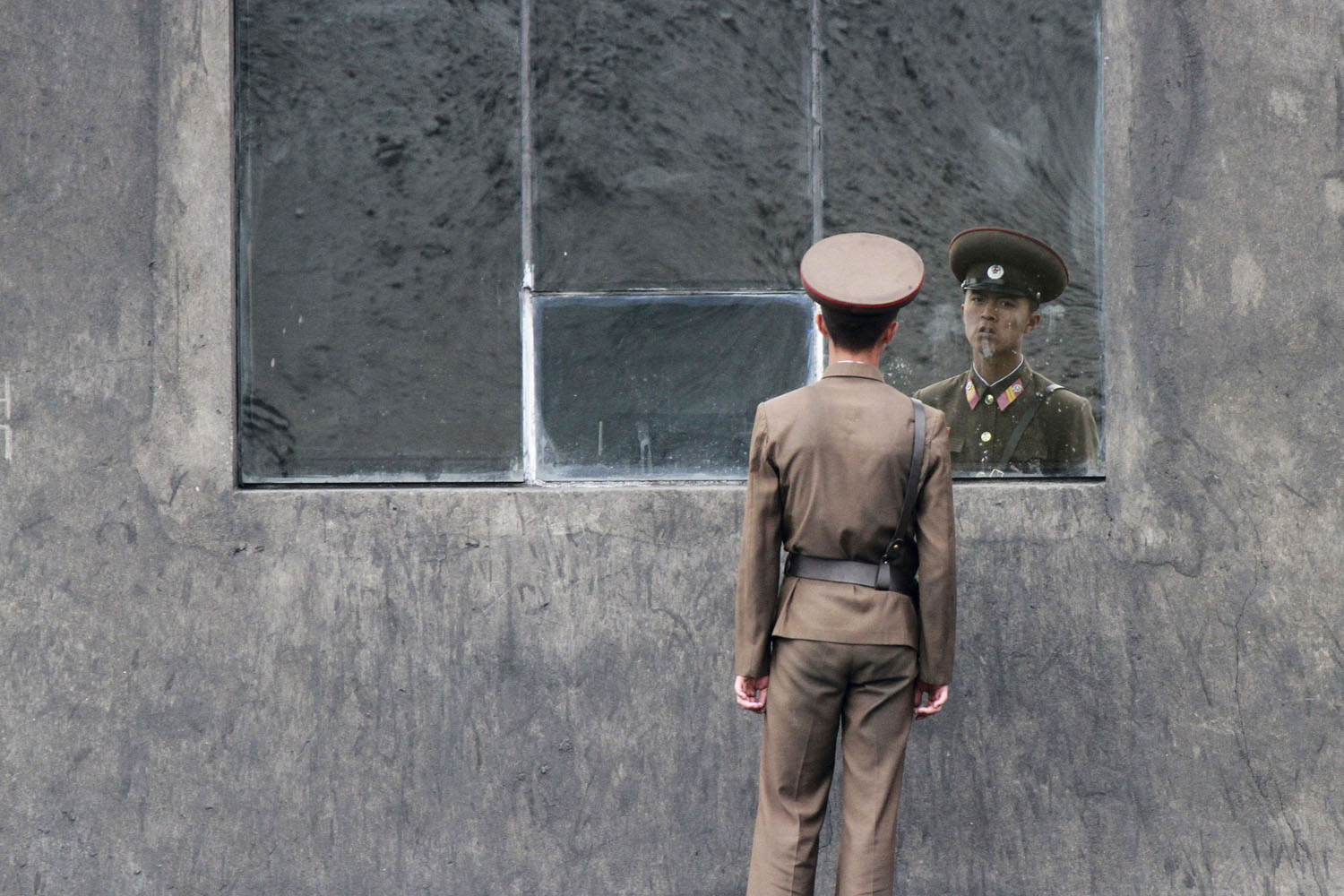 June 24, 2013. A North Korean soldier stands in front of a window along the banks of Yalu River near the North Korean town of Sinuiju, opposite the Chinese border city of Dandong.