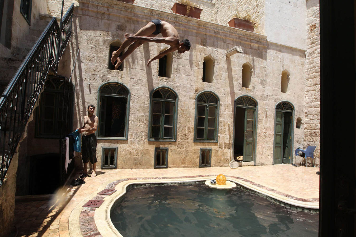 June 24, 2013. A Free Syrian Army fighter dives into a swimming pool inside a house in the old city of Aleppo.