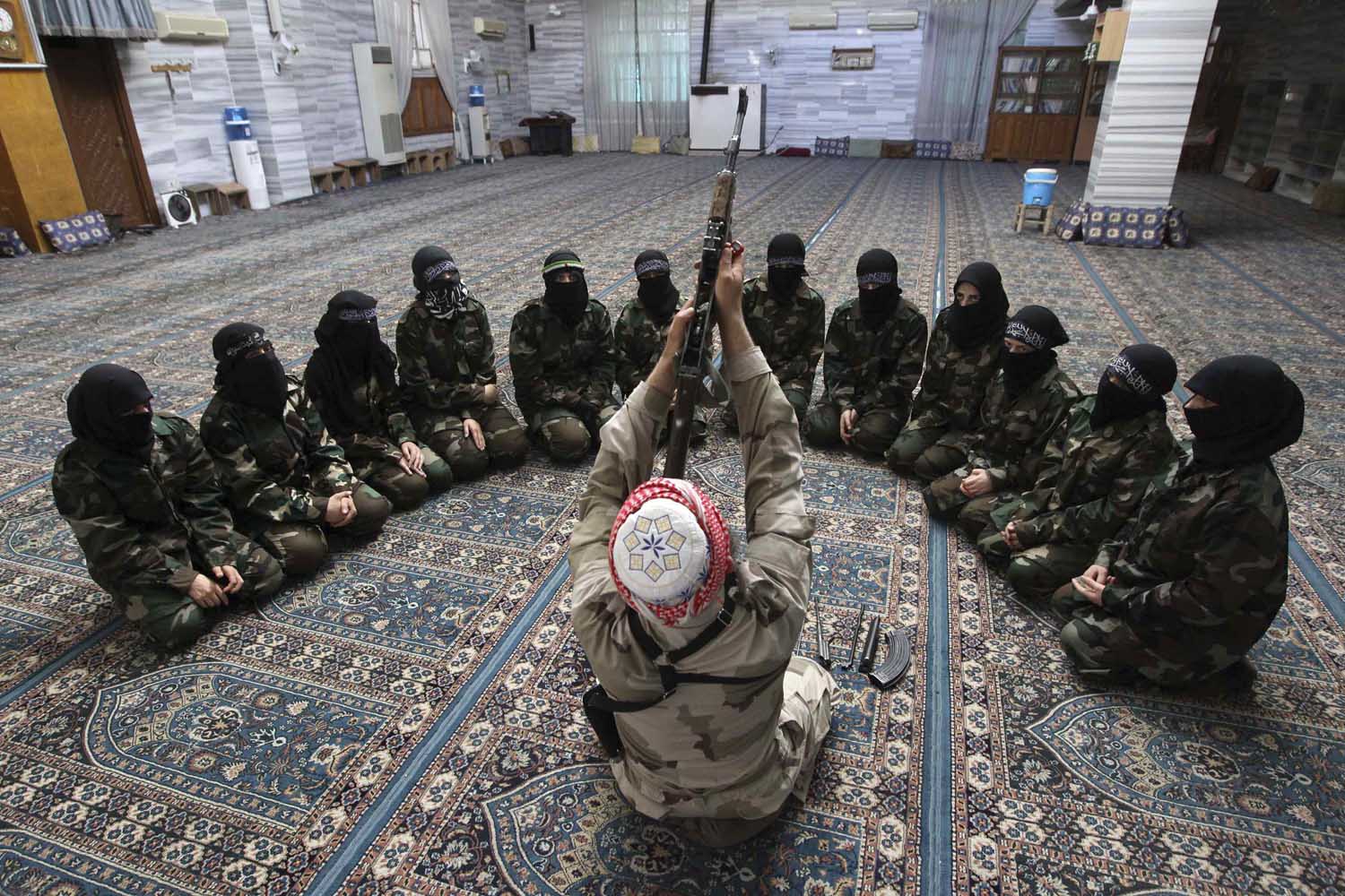 June 24, 2013. Abu al-Taib, the leader of Ahbab Al-Mustafa Battalion, demonstrates to female members as he holds a gun during a military training in a mosque in the Seif El Dawla neighbourhood in Aleppo, Syria.