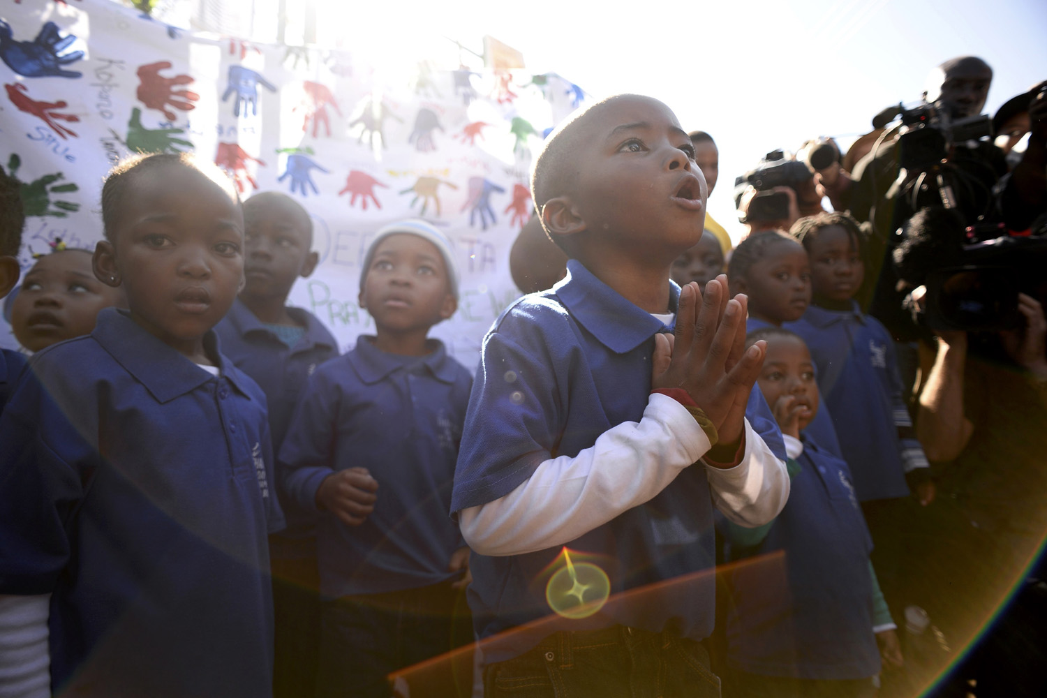 June 26, 2013. A student chants a prayer as his class visits Medi-Clinic Heart Hospital to pay respect where ailing former South African President Nelson Mandela is being treated in Pretoria.