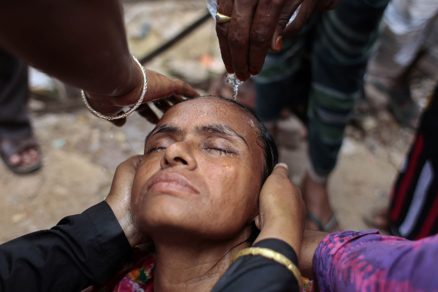 June 24, 2013. Shahida Begum losses consciousness during a protest to demand compensation for the dead and missing workers of a garment factory building collapse, in Savar, near Dhaka, Bangladesh.