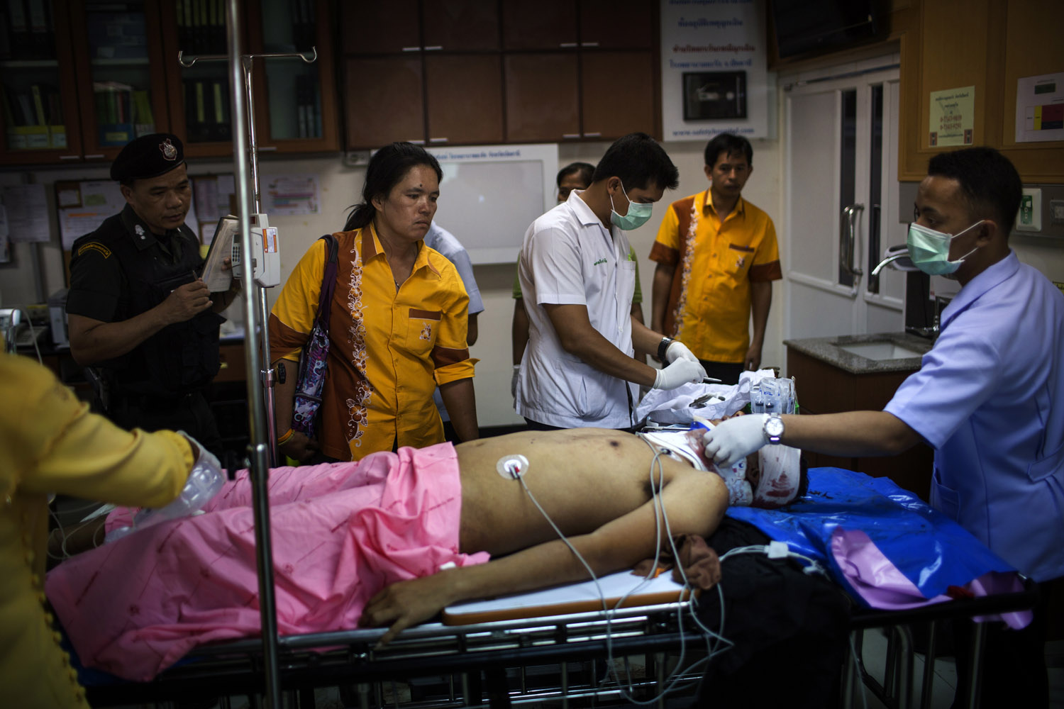 A teacher (second from left) who used to be protected by Chanchote Phetpong looks at his body in the Mass Casualty Zone of Yarang Hospital.