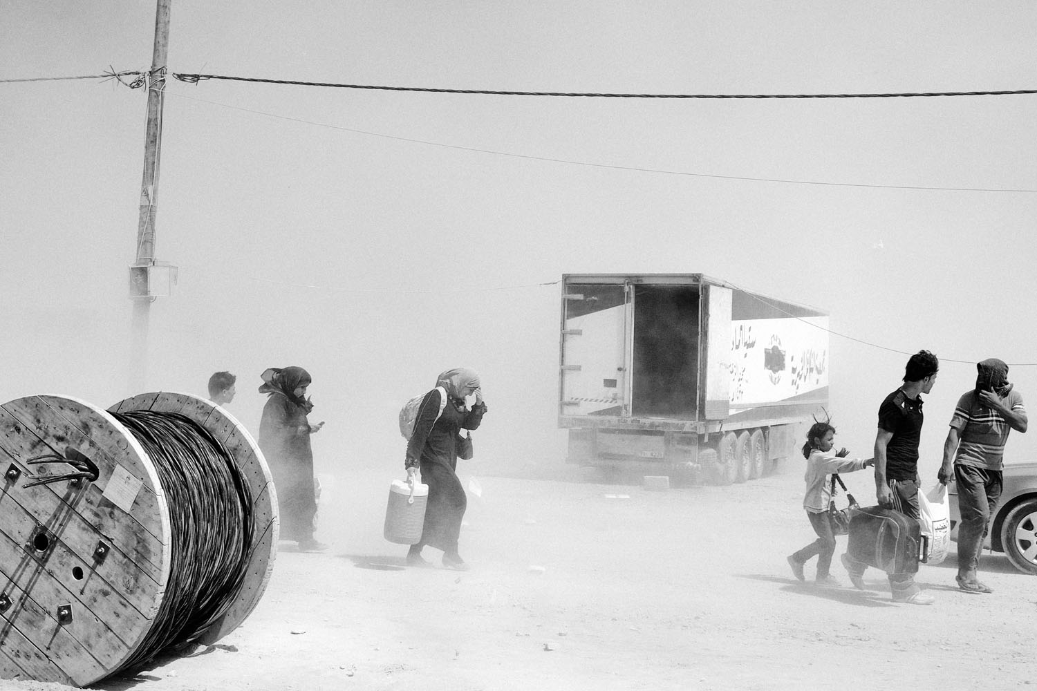 JORDAN. Zaatari. Refugee Camp. August 31, 2012. A Syrian family walk through a sandstorm inside the Zaatari refugee camp near the Syrian border in Jordan. Contact email:New York : photography@magnumphotos.comParis : magnum@magnumphotos.frLondon : magnum@magnumphotos.co.ukTokyo : tokyo@magnumphotos.co.jpContact phones:New York : +1 212 929 6000Paris: + 33 1 53 42 50 00London: + 44 20 7490 1771Tokyo: + 81 3 3219 0771Image URL:http://www.magnumphotos.com/Archive/C.aspx?VP3=ViewBox_VPage&IID=2K7O3RKH3NH6&CT=Image&IT=ZoomImage01_VForm