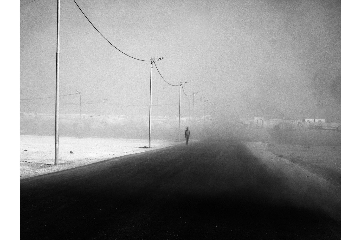 Zaatari, Jordan. June 20313.A man walks through a sandstorm on the edge of the Zaatari refugee camp in Jordan.(Photo by Moises Saman/MAGNUM)