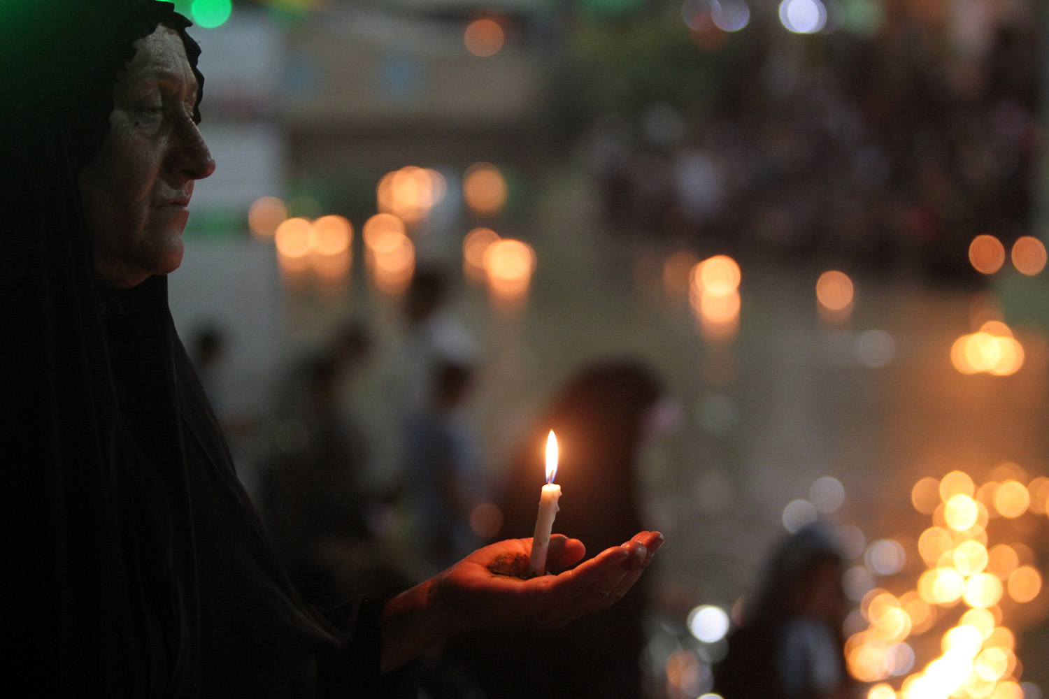 July 25, 2013. A Muslim Shiite woman carries a candle near the shrine of Imam Abbas, one of Shiite Islam's most revered figures, during the Shaabaniya ceremony commemorating the birth of Imam al-Mahdi, the 12th holiest figure for Shiite Muslims, in the central Iraqi city of Karbala.