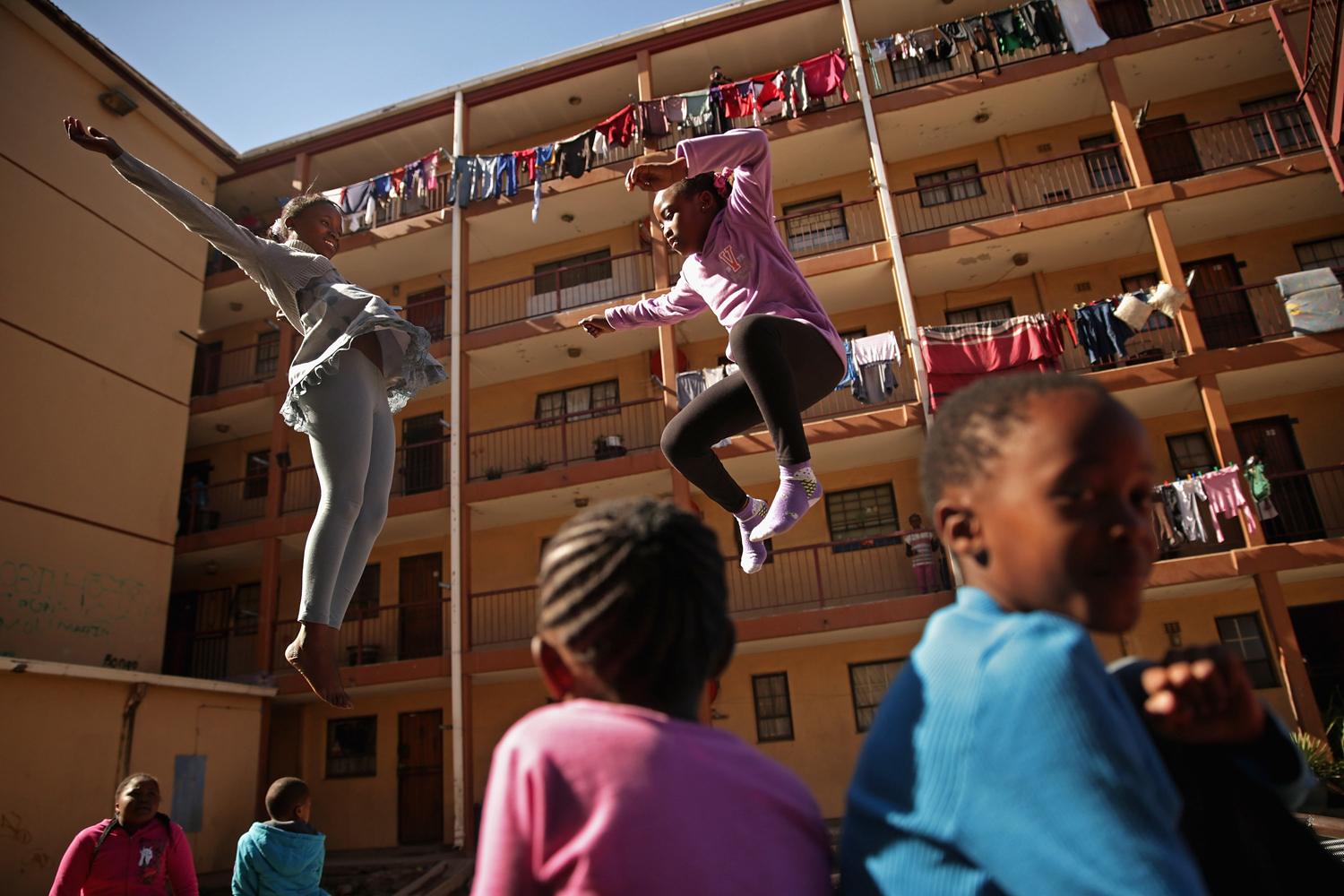 June 26, 2013. Phaphama Nxumalo (L), 12, and Natasha Mbatha, 9, members of the Alexandra Trampoline Club, practices in an alleyway between apartment blocks in Johannesburg, South Africa.