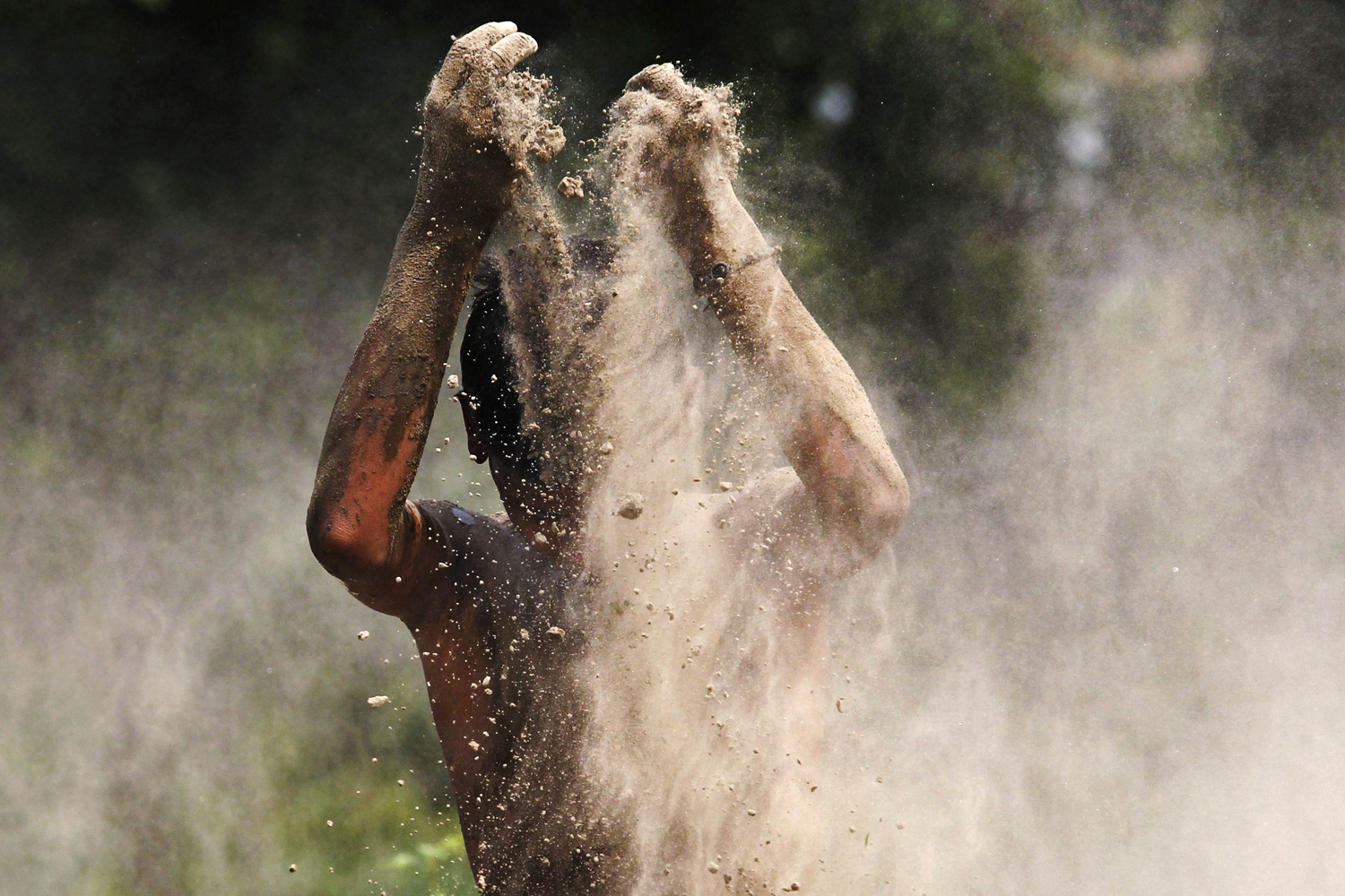 A boy plays with mud on the banks of river Yamuna on a hot day in New Delhi