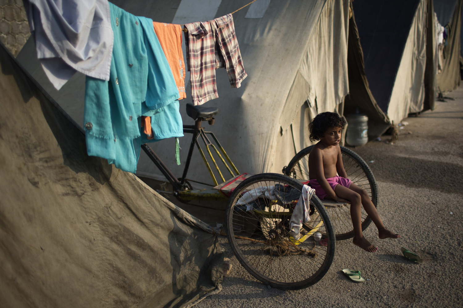 A child displaced by the rising waters of the river Yamuna sits on a cycle cart parked outside makeshift tents at a roadside camp in New Delhi