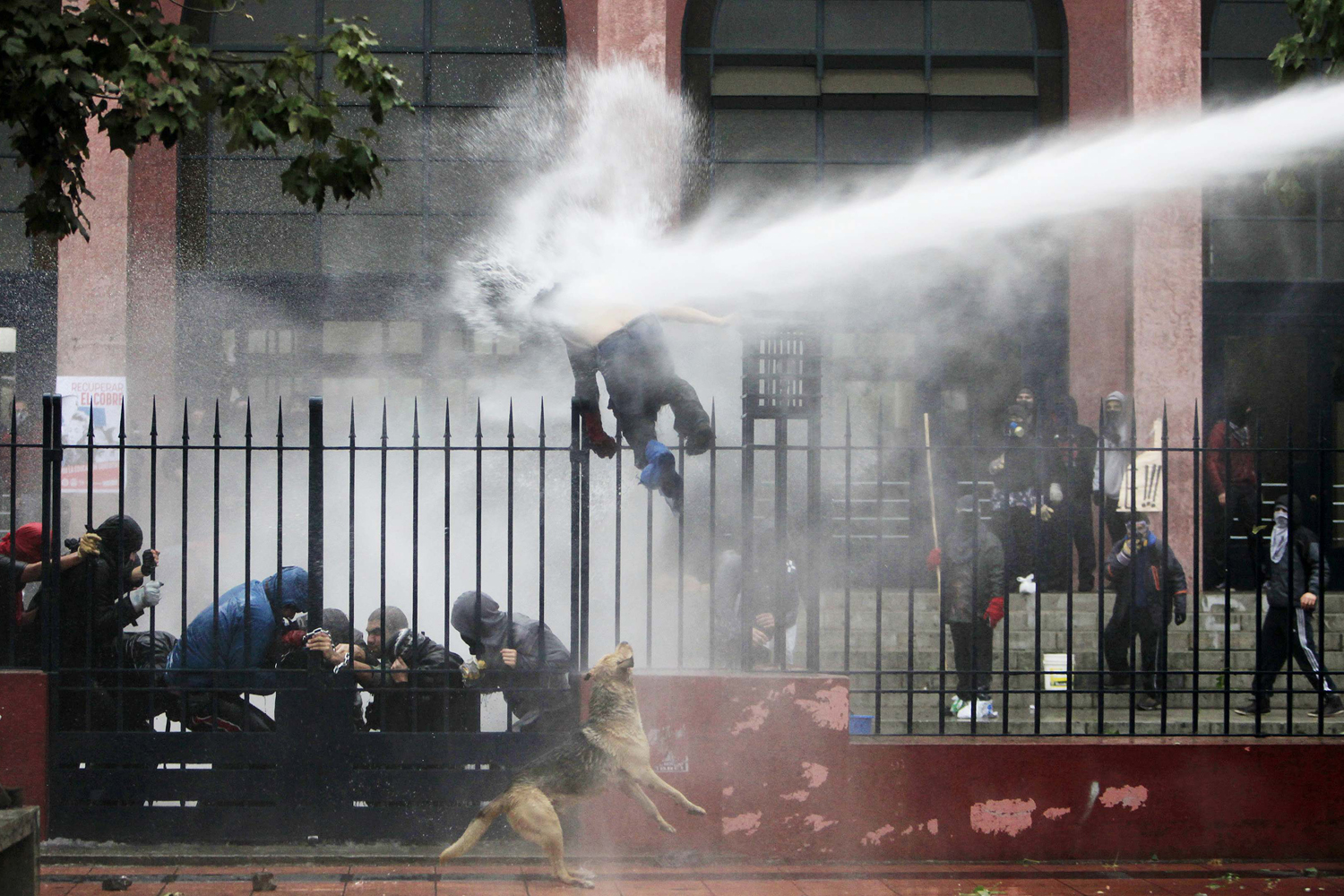 June 26, 2013. A student is hit by a jet of water sprayed by riot police during a protest against the government to demand changes in the public state education system, in Santiago.