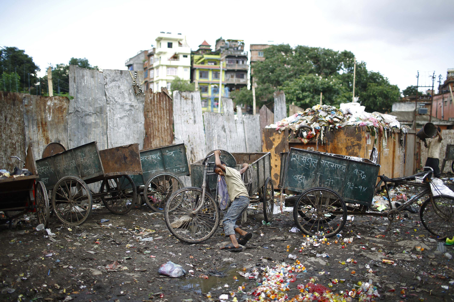 A boy pushes a rickshaw used to carry garbage at the dumping site along the banks of Bishnumati River in Kathmandu