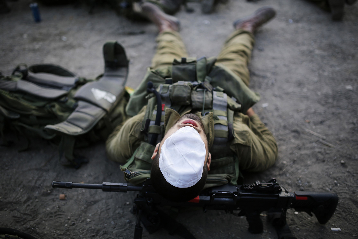 June 27, 2013. An Israeli soldier of the paratrooper brigade covers his face with a kippah, or skullcap, as he takes a break during a march near Jerusalem, marking the completion of their advanced training, at the end of which they receive a red paratrooper beret.