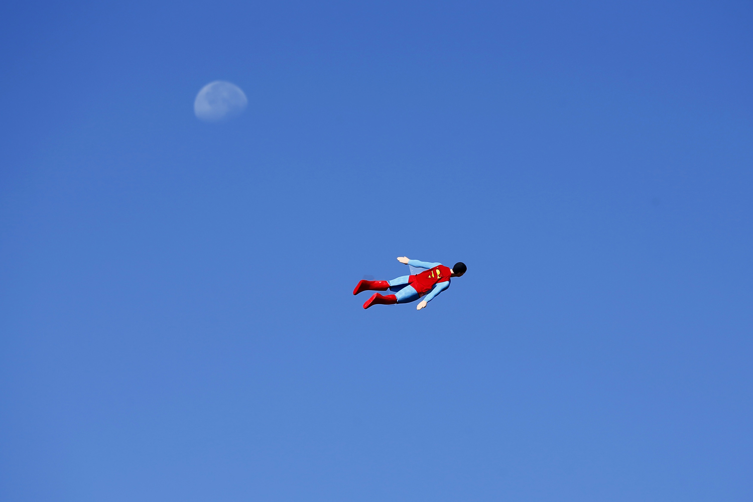 June 27, 2013. A radio-controlled Superman plane, flown by designer Otto Dieffenbach, passes the moon during a test flight in San Diego, California.