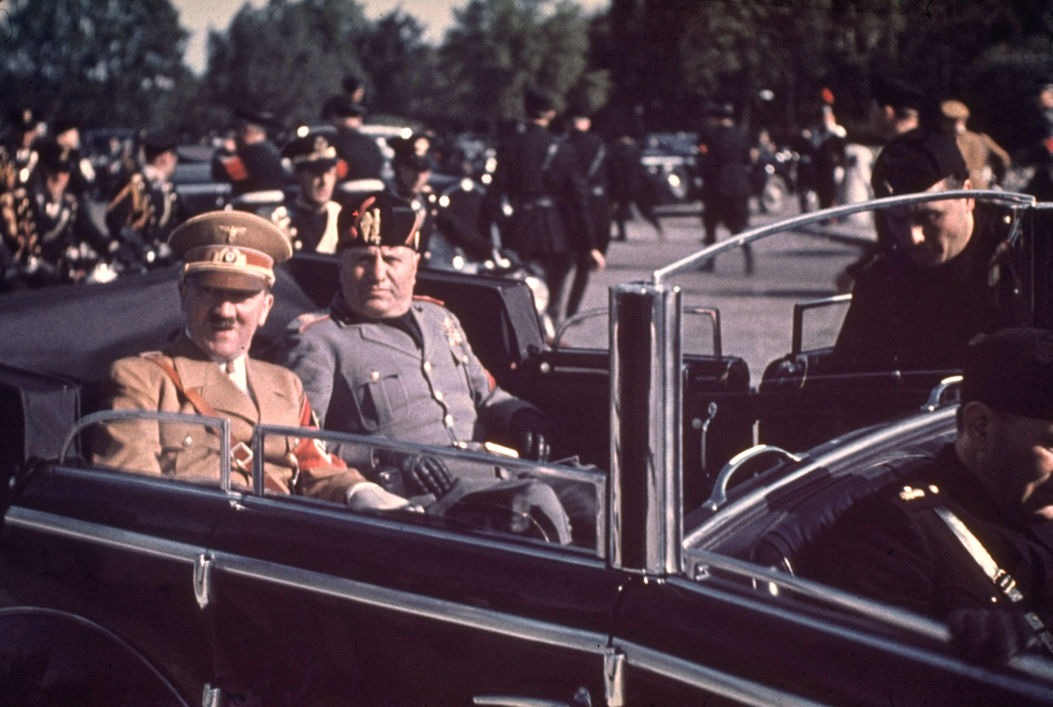 Adolf Hitler and Benito Mussolini ride through streets flanked by black-uniformed Italian Fascists during Hitler's 1938 state visit to Italy.