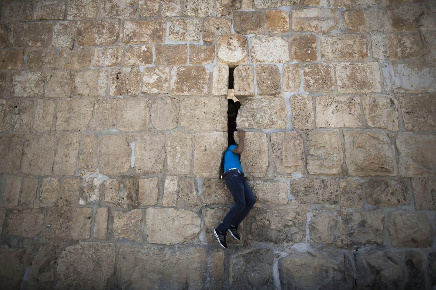 July 12, 2013. A Palestinian Muslim worshipper sneaks through a hole in the Old City wall near the Lions Gate after prayers at the Al Aqsa Mosque in Jerusalem's Old City.