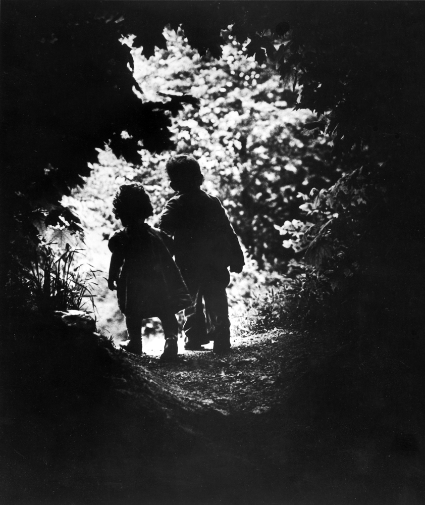 The children of photographer W. Eugene Smith walk hand-in-hand in the woods behind his home, 1946.