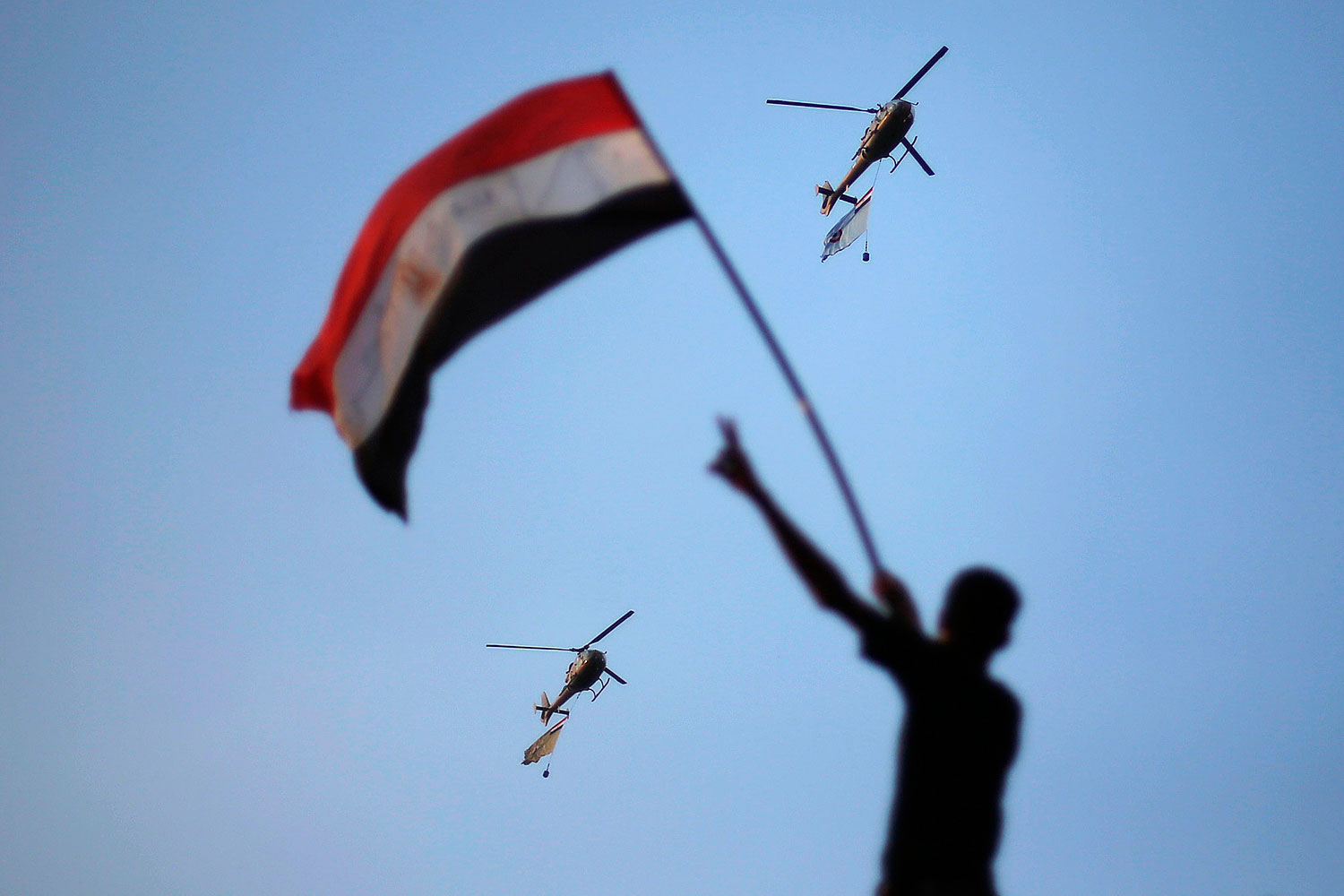 July 1, 2013. Egyptian military helicopters trailing national flags circled over Tahrir Square during a protest demanding that Egyptian President Mohamed Morsi resign in Cairo.