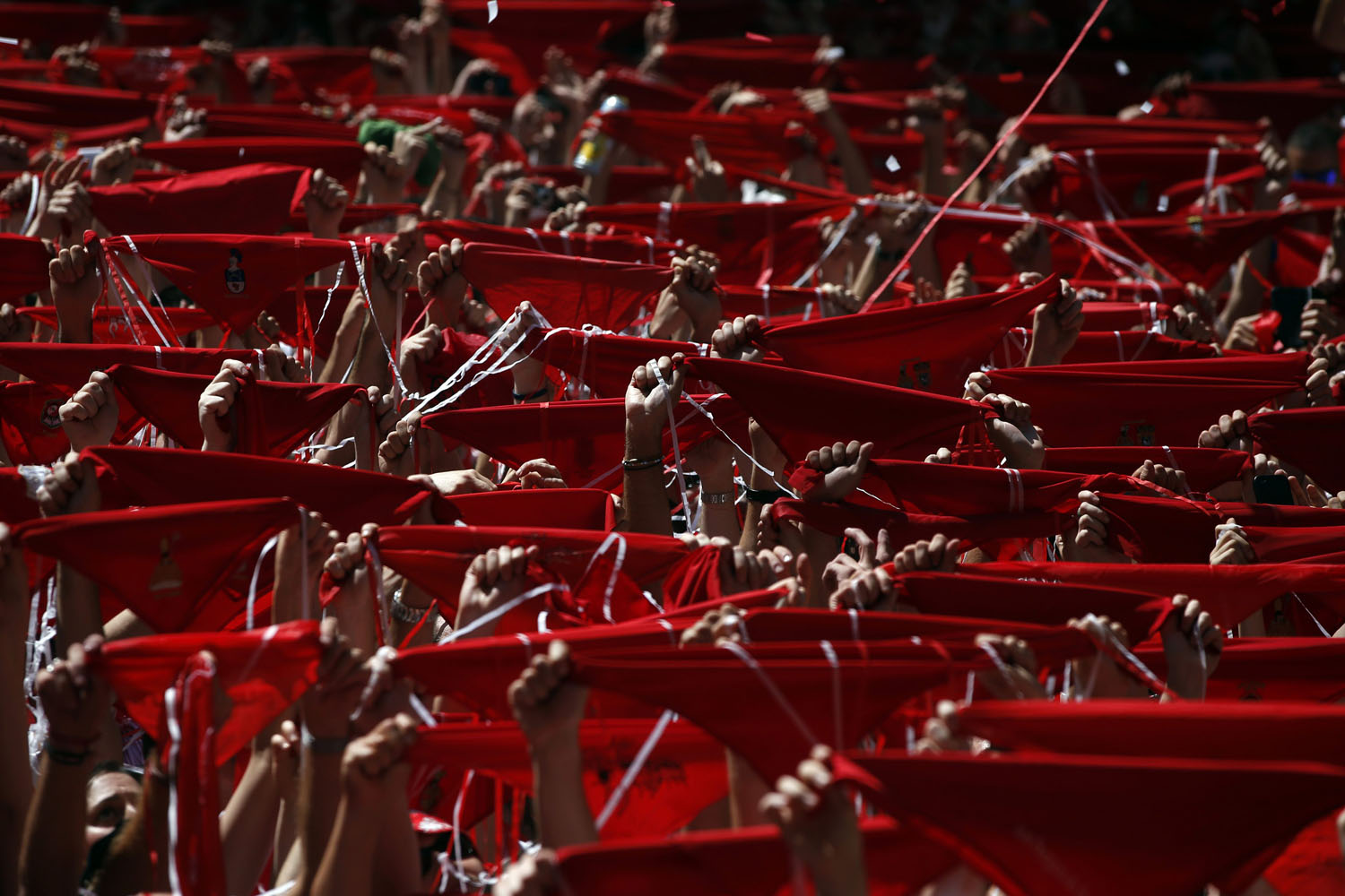 Revellers hold up their red scarves during the start of the San Fermin festival in Pamplona