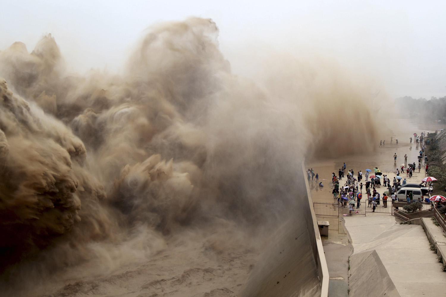 Visitors watch water gushing from the section of the Xiaolangdi Reservoir on the Yellow River, during a sand-washing operation in Jiyuan