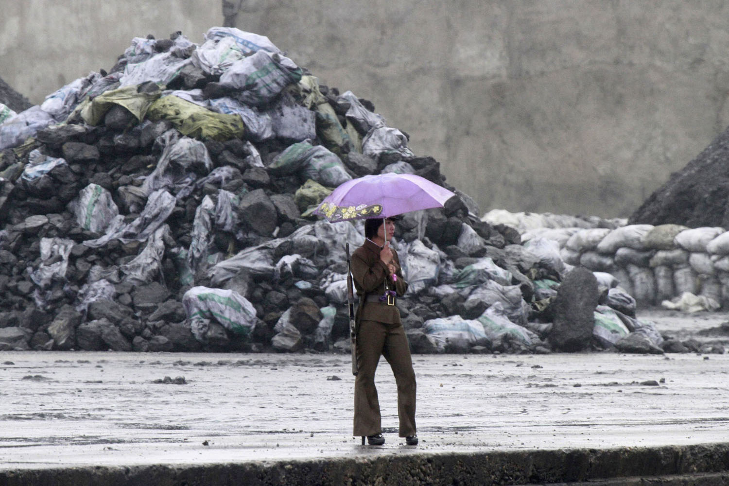 A North Korean soldier holds an umbrella as she stands guard along the banks of the Yalu River