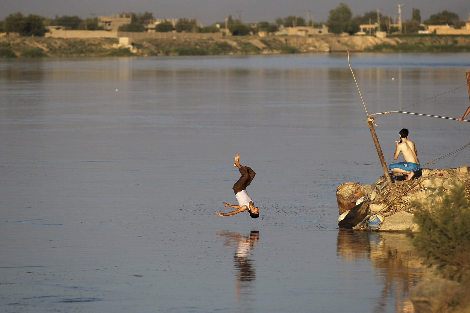 A member of the Free Syrian Army dives into the Euphrates river in Deir al-Zor