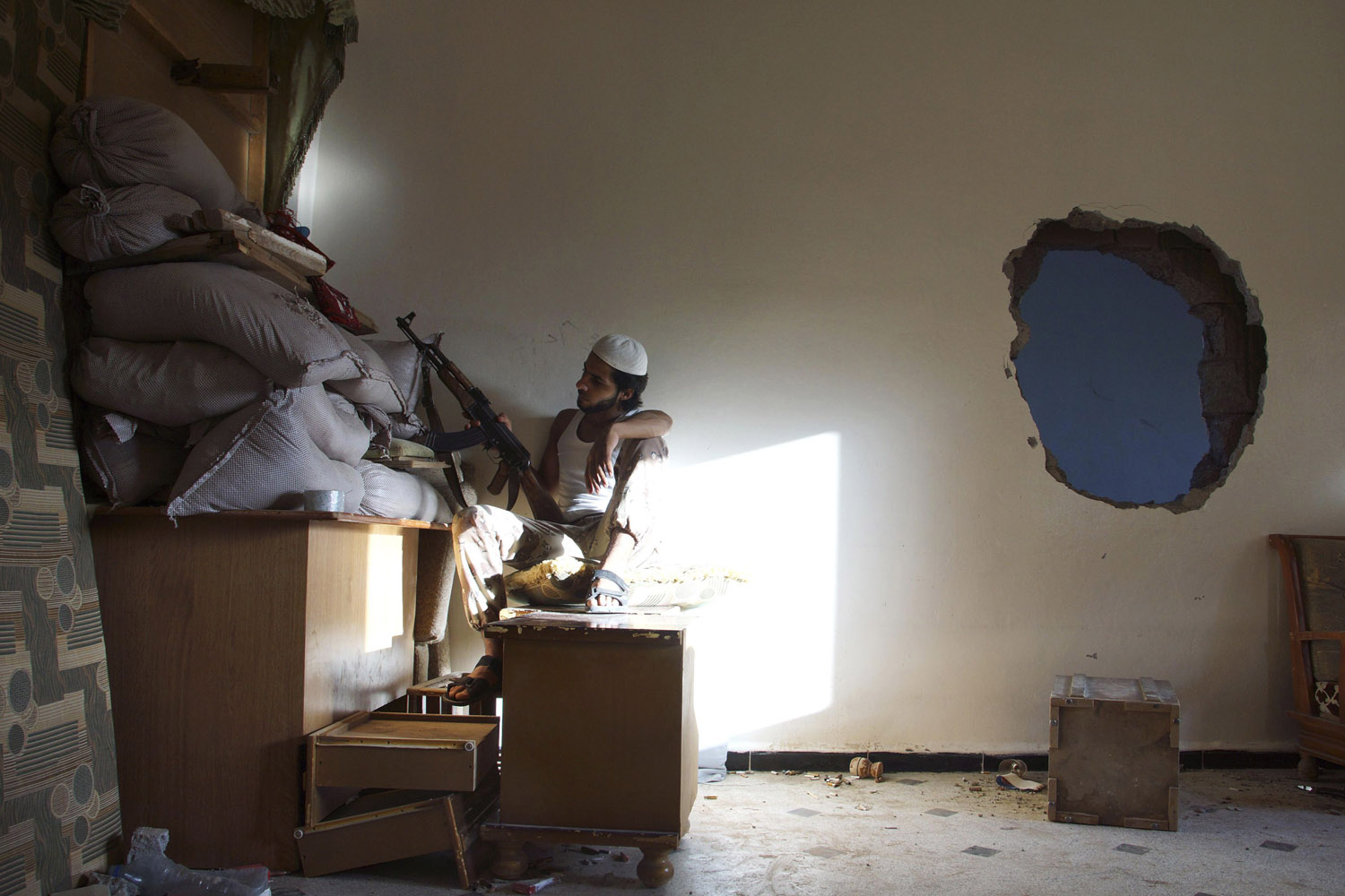 A Free Syrian Army fighter takes cover behind sandbags inside a house as in Deir al-Zor