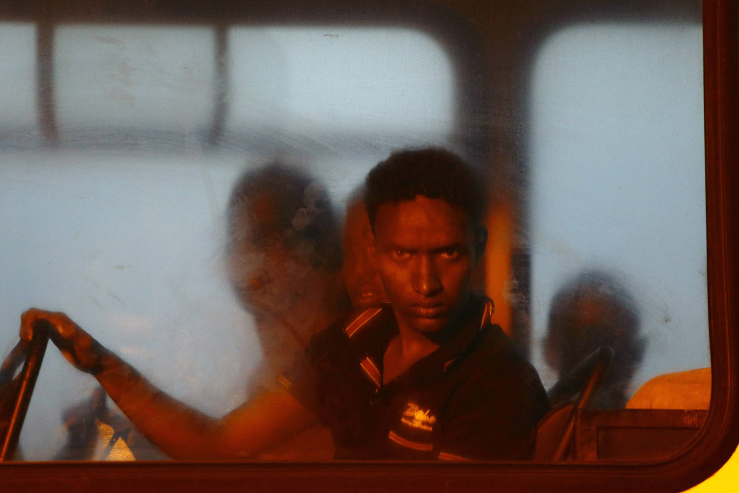 A would-be immigrant looks out of a window on a police bus after arriving at the AFM Maritime Squadron base at Haywharf in Valletta
