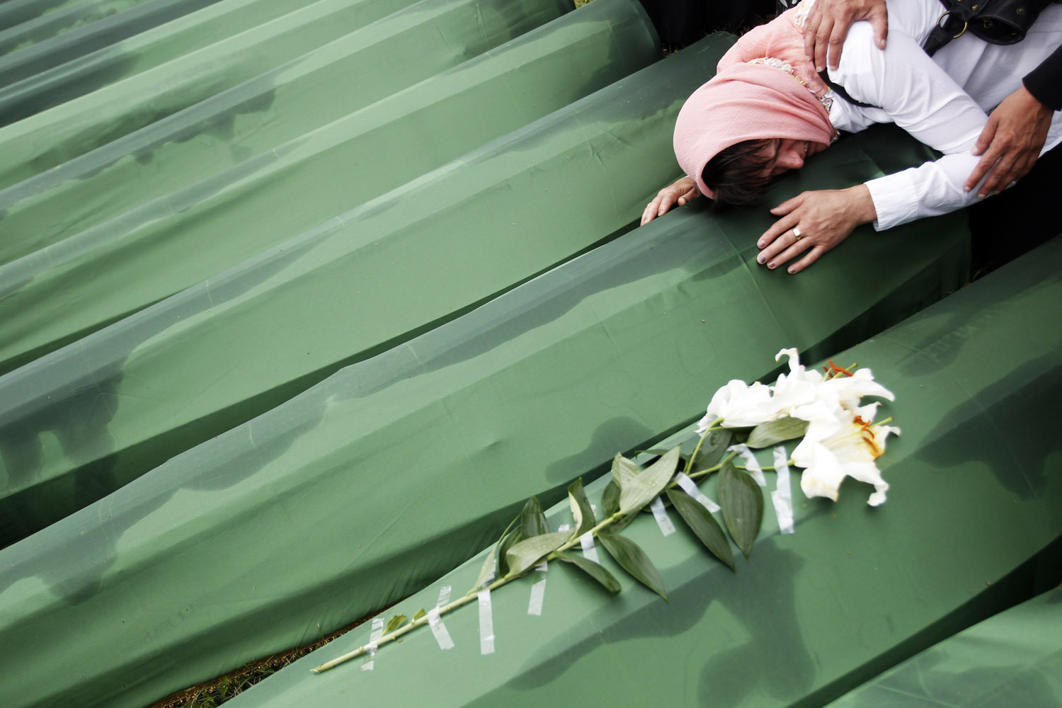 A Bosnian woman cries on the coffin of a relative, which is one of the 409 coffins of newly identified victims from the 1995 Srebrenica massacre