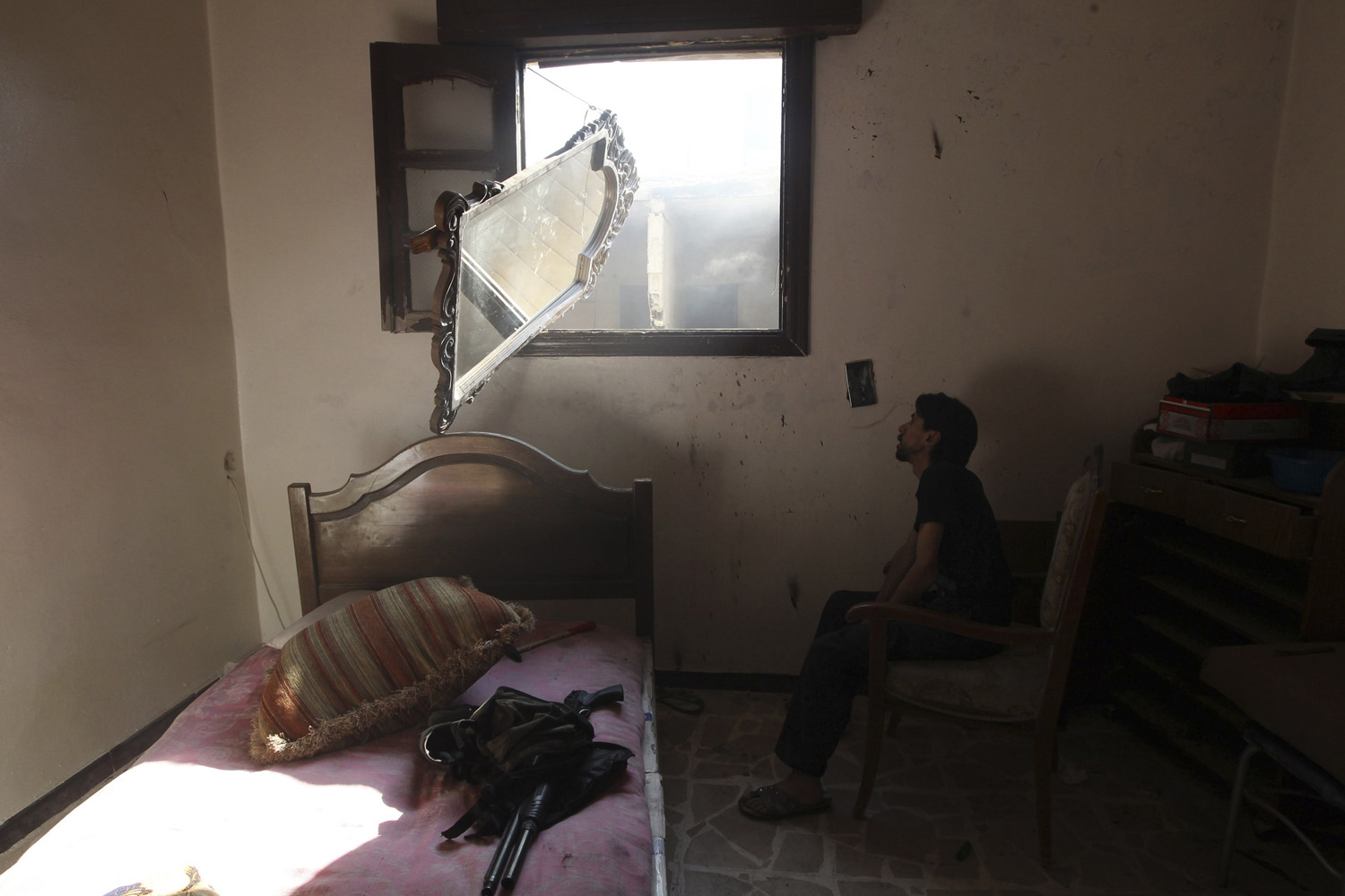 A Free Syrian Army fighter takes up a position as he uses a mirror to look out for snipers loyal to Syria's President Bashar al-Assad in Aleppo's Salaheddine neighborhood,
