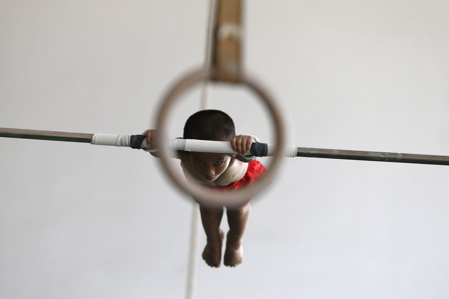 Six-year-old gymnast practices on a horizontal bar at the gymnastics hall of a sports school in Jiaxing
