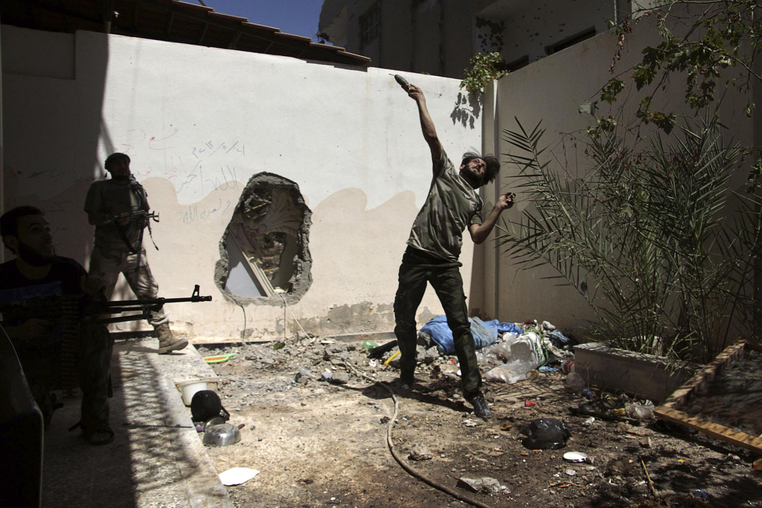 July 14, 2013. A Free Syrian Army fighter throws a homemade bomb towards forces loyal to Syria's President Bashar al-Assad as fellow fighters watch in Deir al-Zor.
