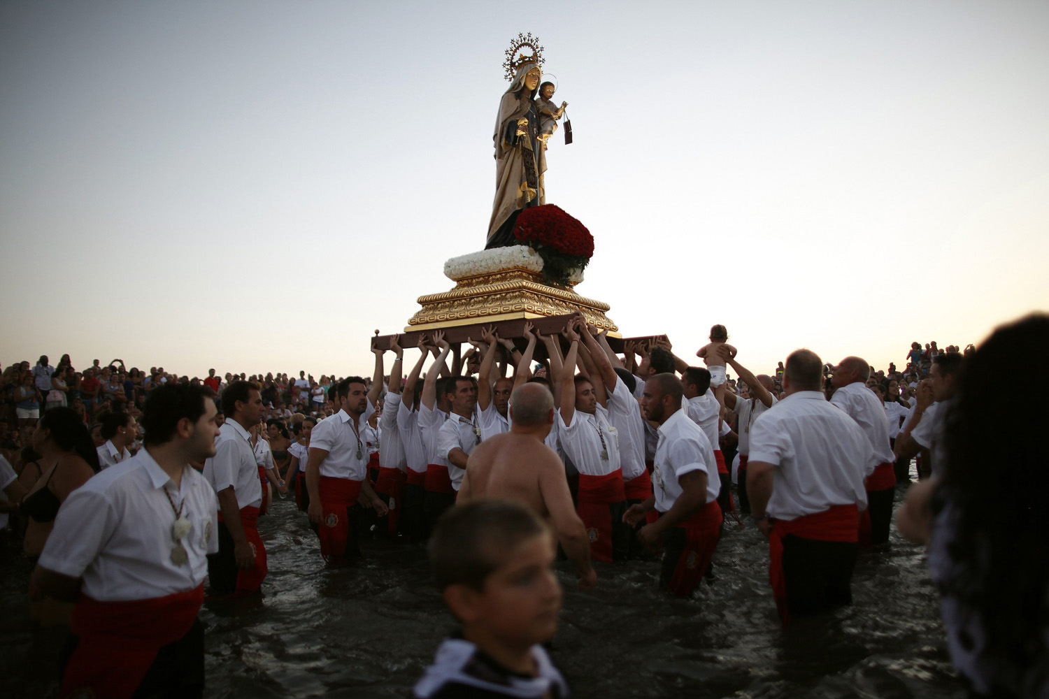 July 16, 2013. Men in traditional costumes carry a statue of the El Carmen Virgin into the sea during a procession in Malaga, southern Spain.