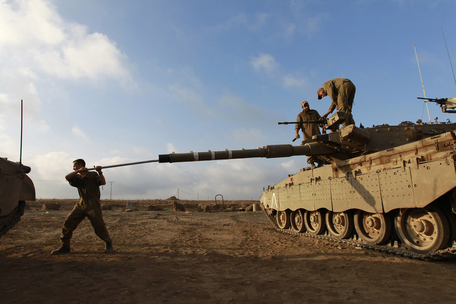 July 17, 2013. An Israeli soldier cleans the barrel of a tank near the border with Syria in the Israeli-occupied Golan Heights.