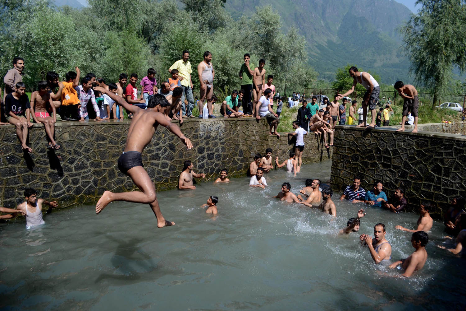 July 14, 2013. A Kashmiri Muslim boy jumps in a spring during a hot Ramadan day in the outskirts of Srinagar as Kashmir Valley undergoes a heat wave during the holy month.