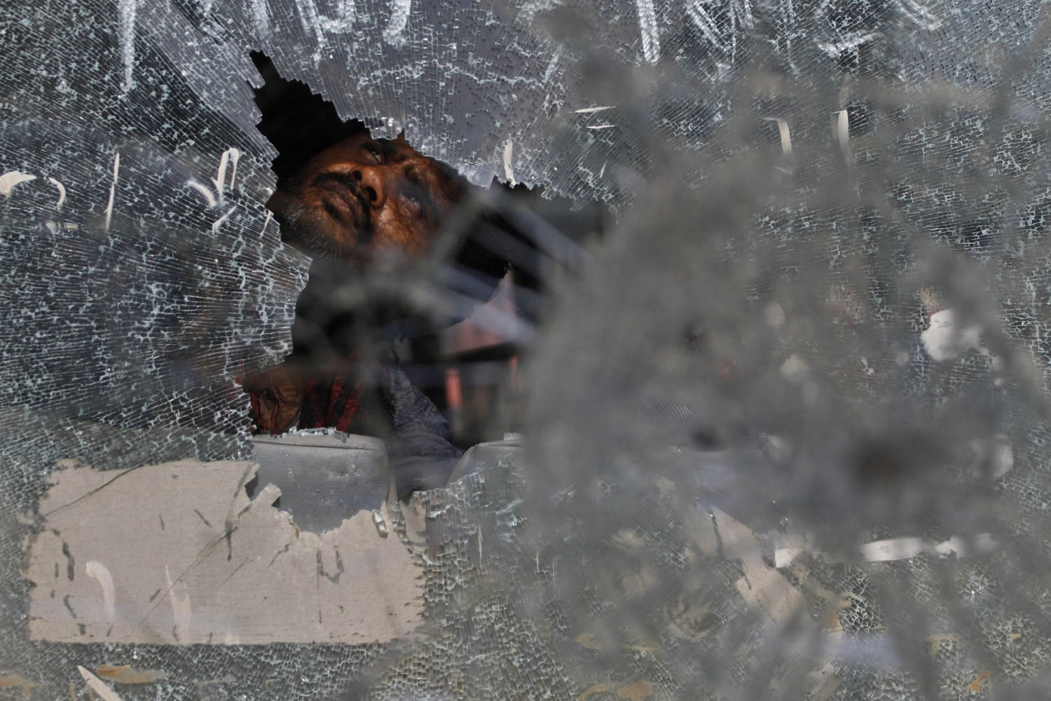 July 15, 2013. A driver inspects one of the government buses damaged by students protesting against caste-based affirmative action in recruitment examinations for government jobs in Allahabad, India.
