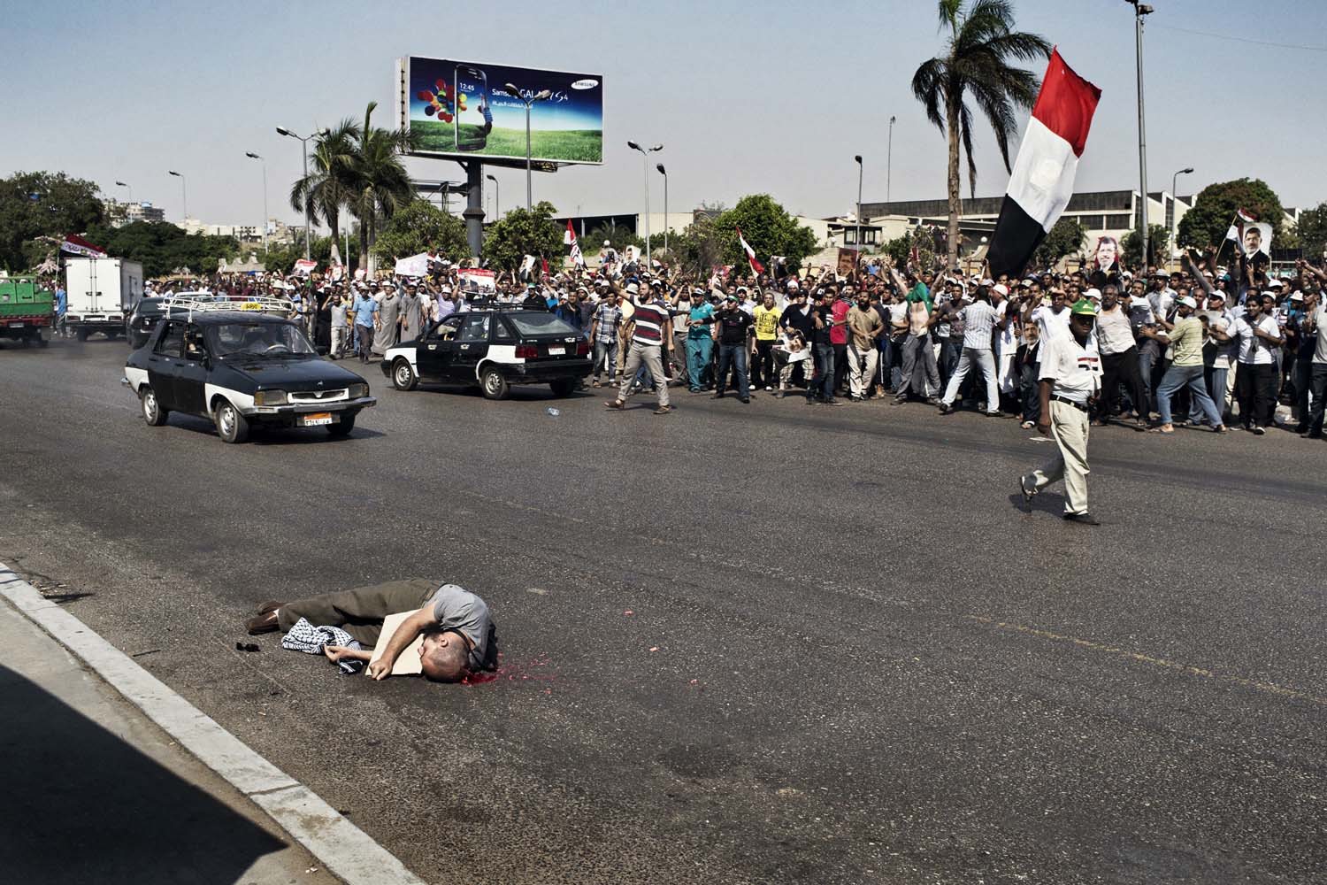 July 5, 2013. Egyptian troops opened fire on mostly Islamist protesters marching on the Republican Guard headquarters.  A man lies on the road after being shot. He crossed the road to try to put a poster of Morsi on the barbed wire next to the Republican Guard barracks, the last known location of the deposed President.