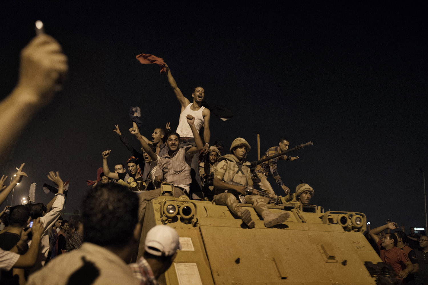 July 5, 2013. Anti-Morsi protestors and soldiers drive down the 6th October Bridge on armored vehicles.
                              The Cairo clashes abated, at least temporarily, after a half dozen armored
                              vehicles full of soldiers with shotguns and tear gas deployed on the
                              bridge and headed toward the pro-Morsi crowd, firing their weapons.