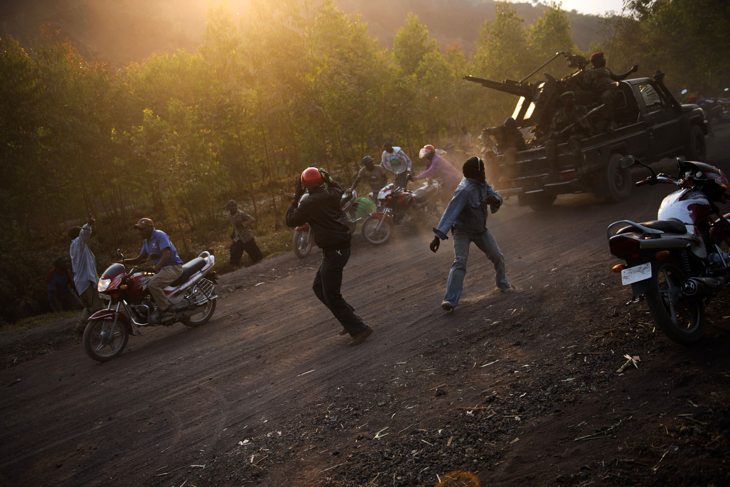 July 15, 2013. Civilians react to shell fire erupting as Congolese armed forces drive through the area of Munigi on the outskirts of Goma in the east of the Democratic Republic of the Congo.