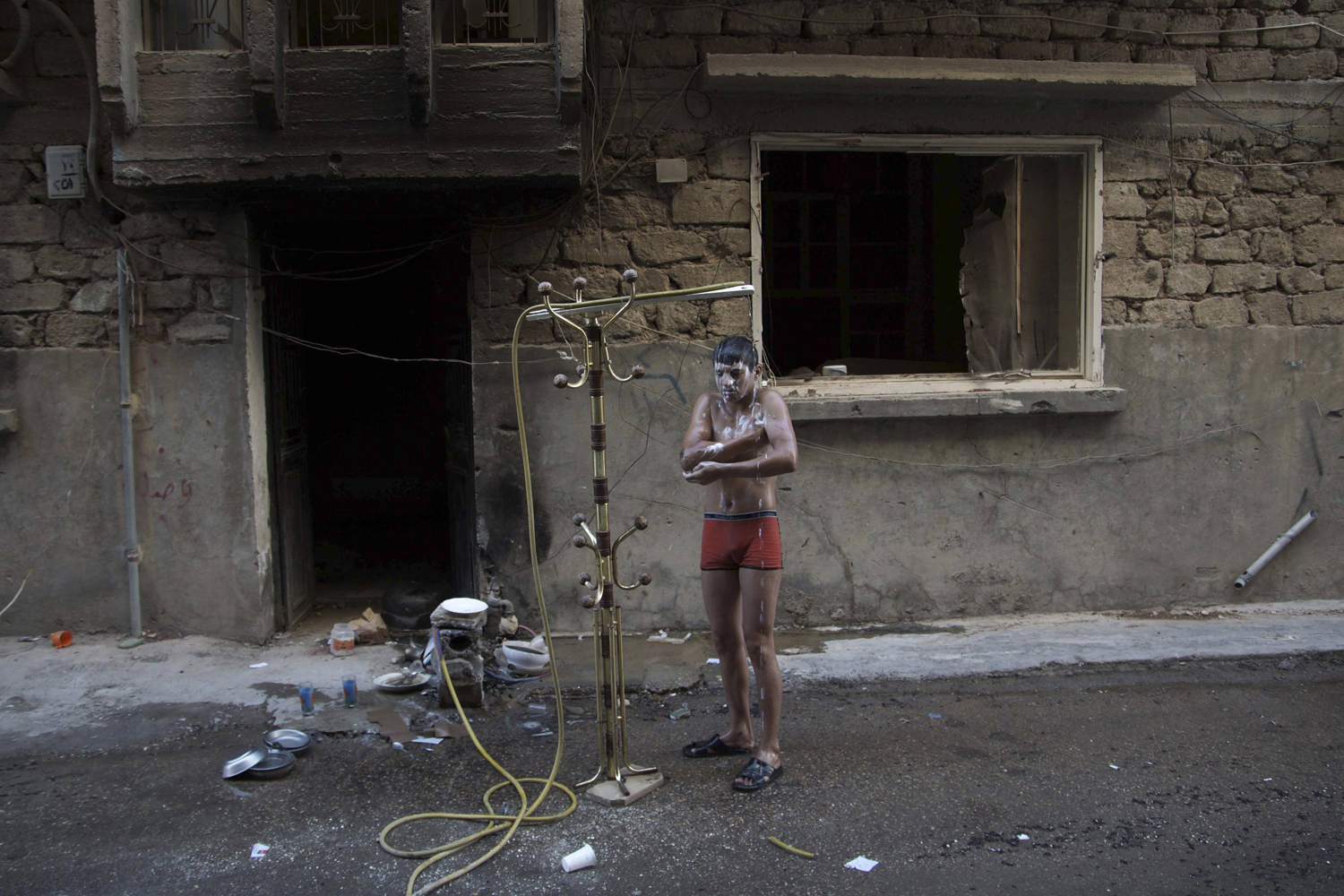 July 17 , 2013. A Free Syrian Army fighter takes a shower outdoors to beat the heat in Deir al-Zor.