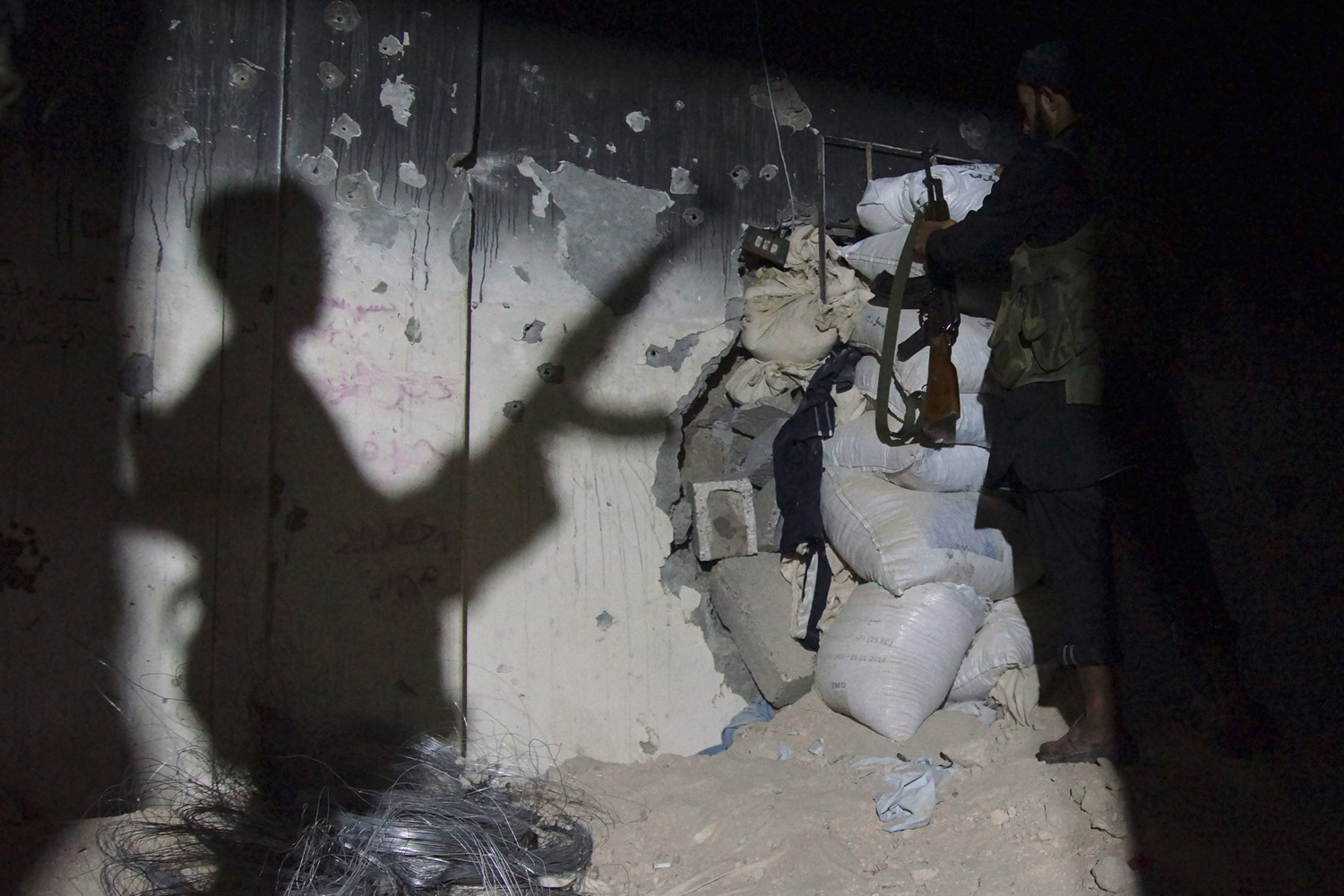A Free Syrian Army fighter carries his weapon as he stands inside a room in Deir al-Zor