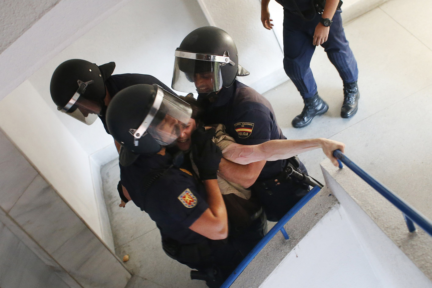 Spanish riot police drag an anti-eviction activist down a staircase during the eviction of Susana Santiago Montoya and her family in Madrid
