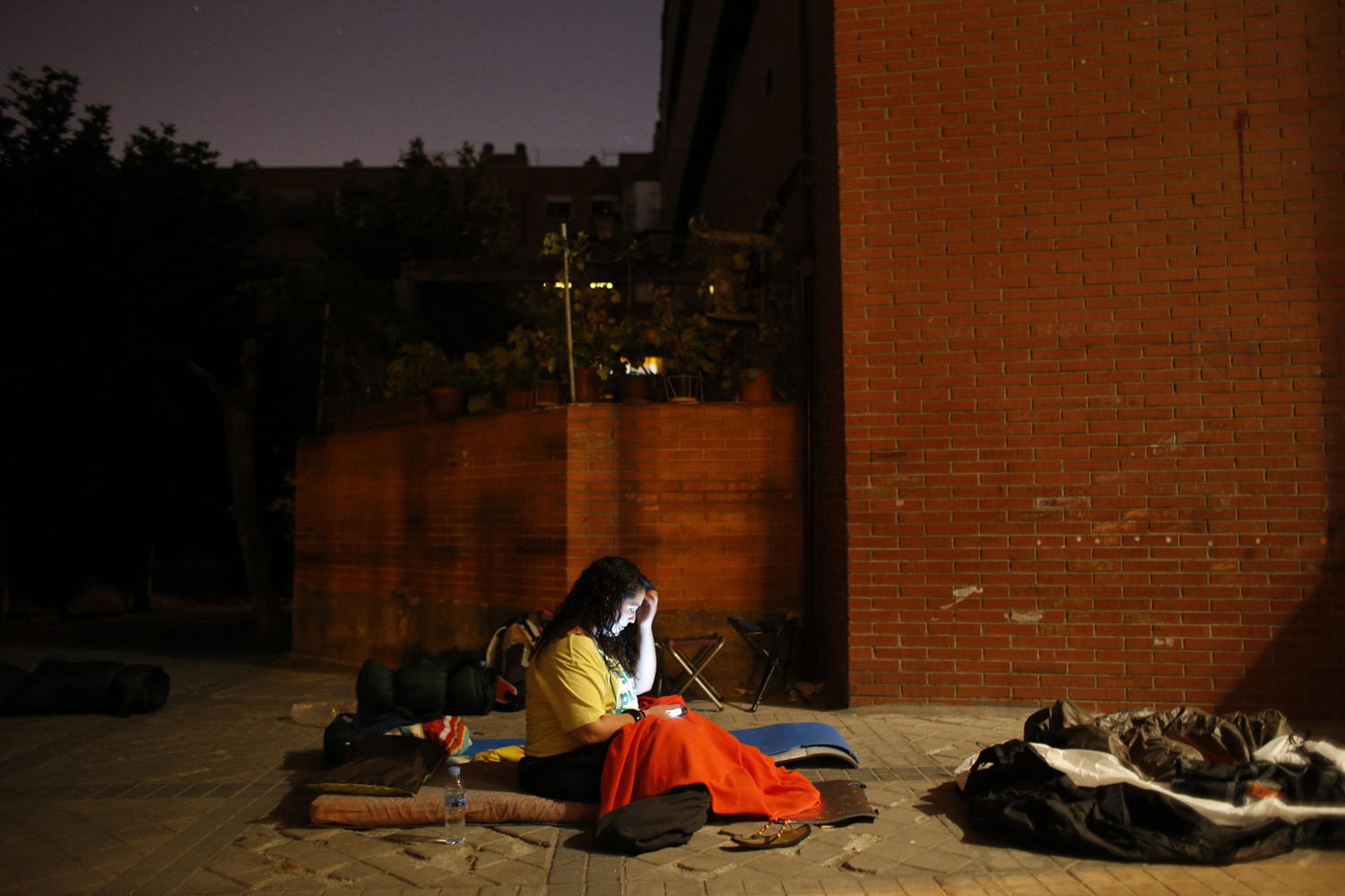 Anti-eviction activist checks her phone as she camps outside the home of Susana Santiago Montoya and her family to try to prevent her eviction in Madrid