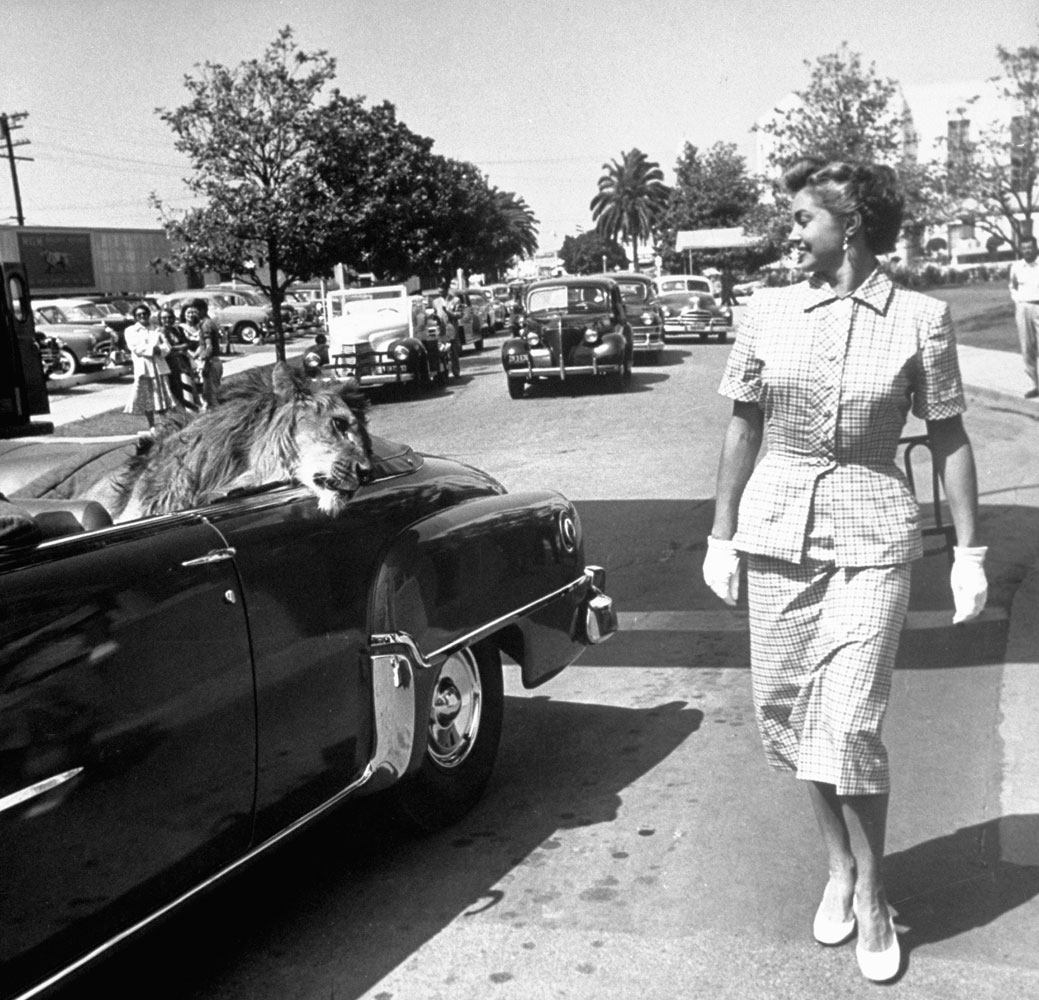 From a chauffer-driven convertible Fagan trades glances with fellow M-G-M star Esther Williams