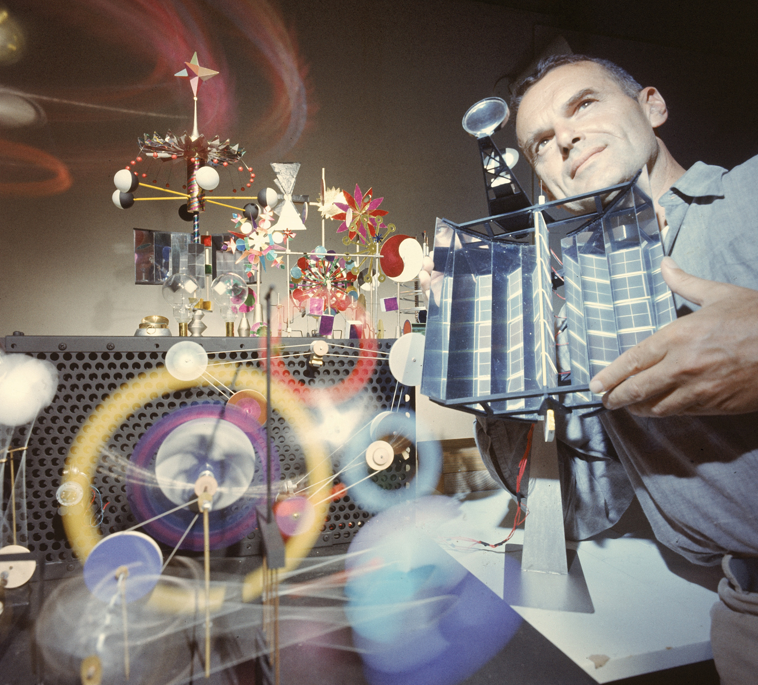 American architect and designer Charles Eames holds his whimsical, solar-powered "Do Nothing Machine" in August 1957.