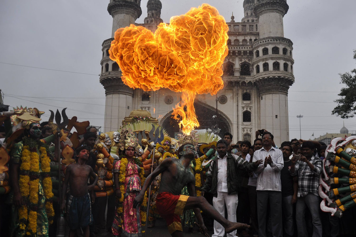 A performer blows fire from his mouth as he performs in front of the historical monument Charminar during the annual Hindu religious festival of Bonalu in Hyderabad