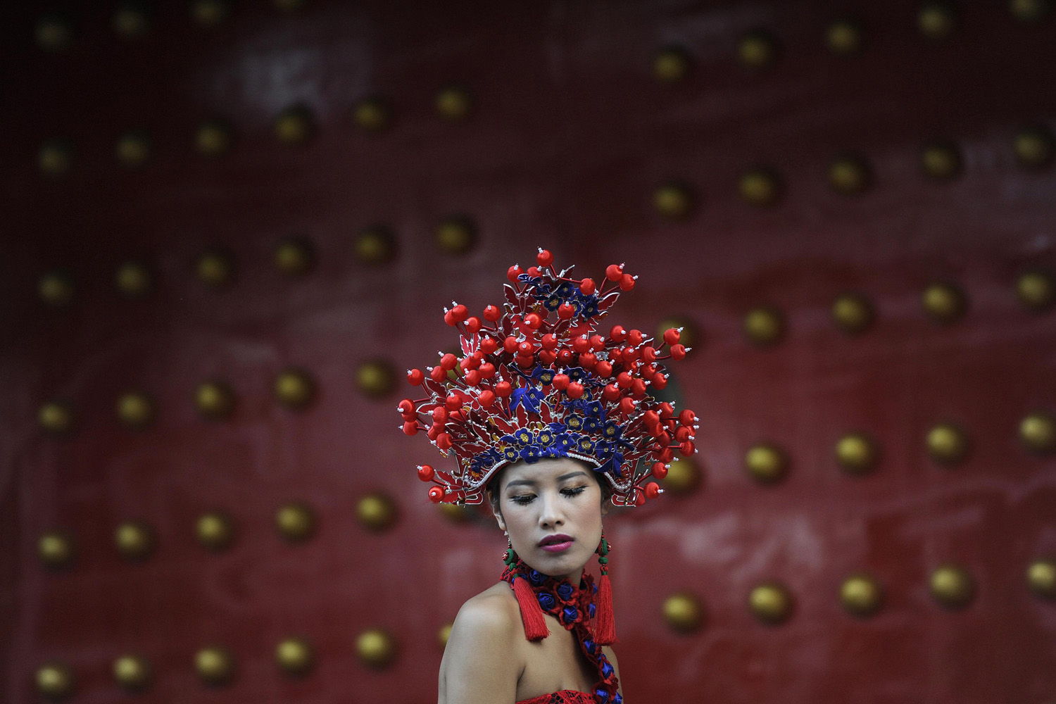 A woman wearing a dress and a headgear inspired by traditional Chinese costume poses for pictures in Lijiang