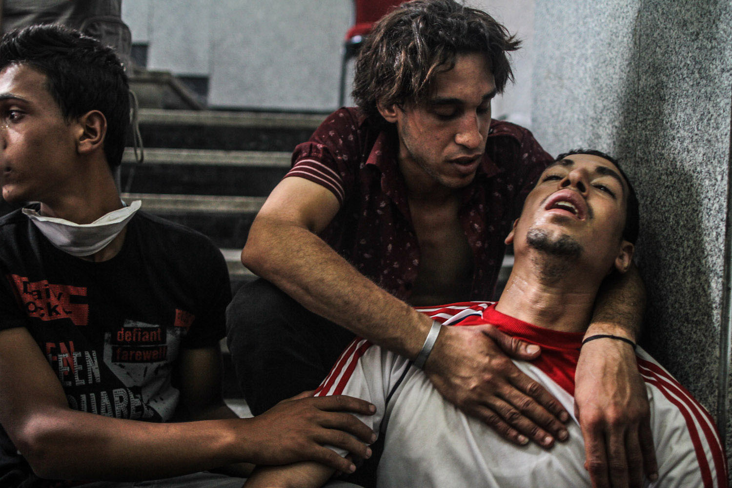 July 27, 2013. A brother of one of the victims is comforted by friends outside the room being used as a makeshift morgue. He kept repeating: “We came together. We have to go home together.”