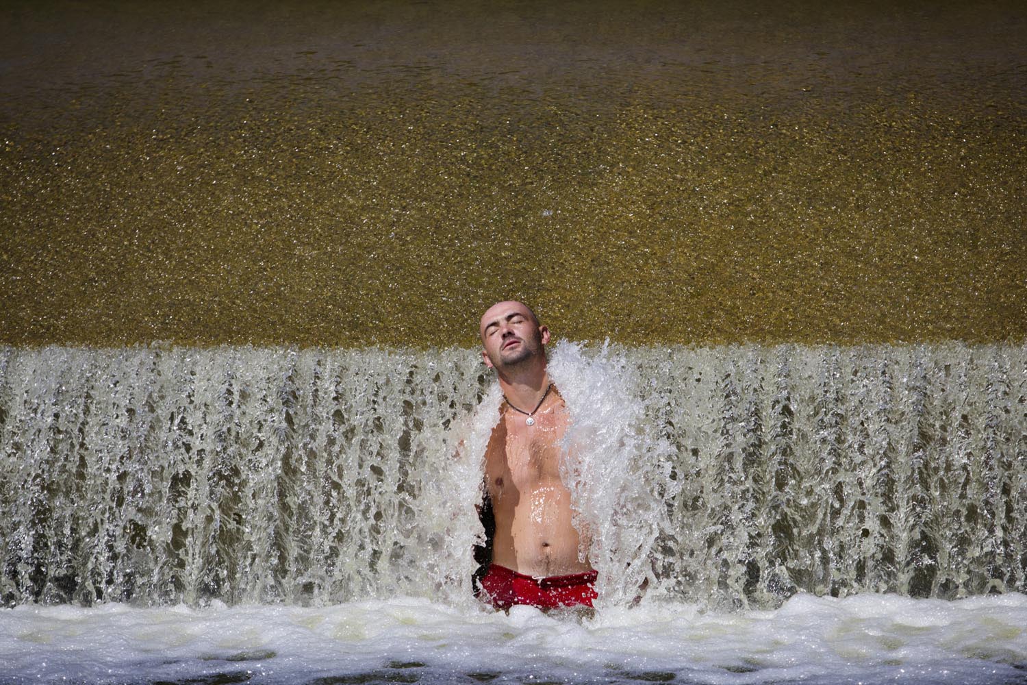 July 28, 2013. A man cools off at a weir of the Berounka river near Dobrichovice, Czech Republic.