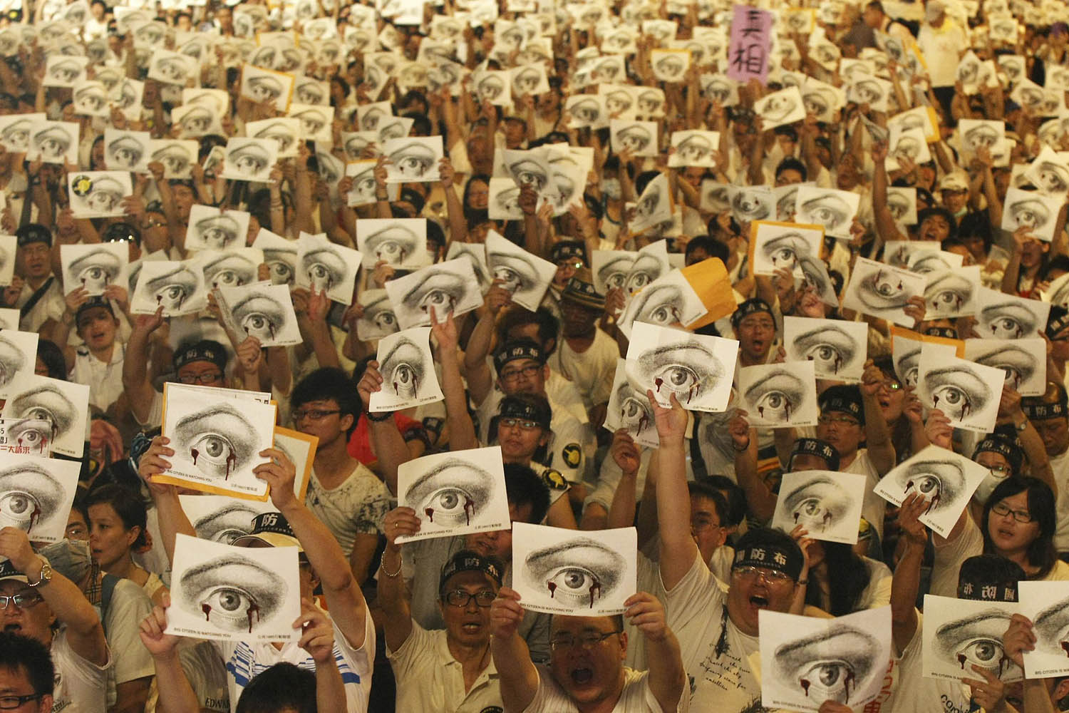 People, holding placards of a bleeding eye, take part in a demonstration in front of the Presidential Office in Taipei