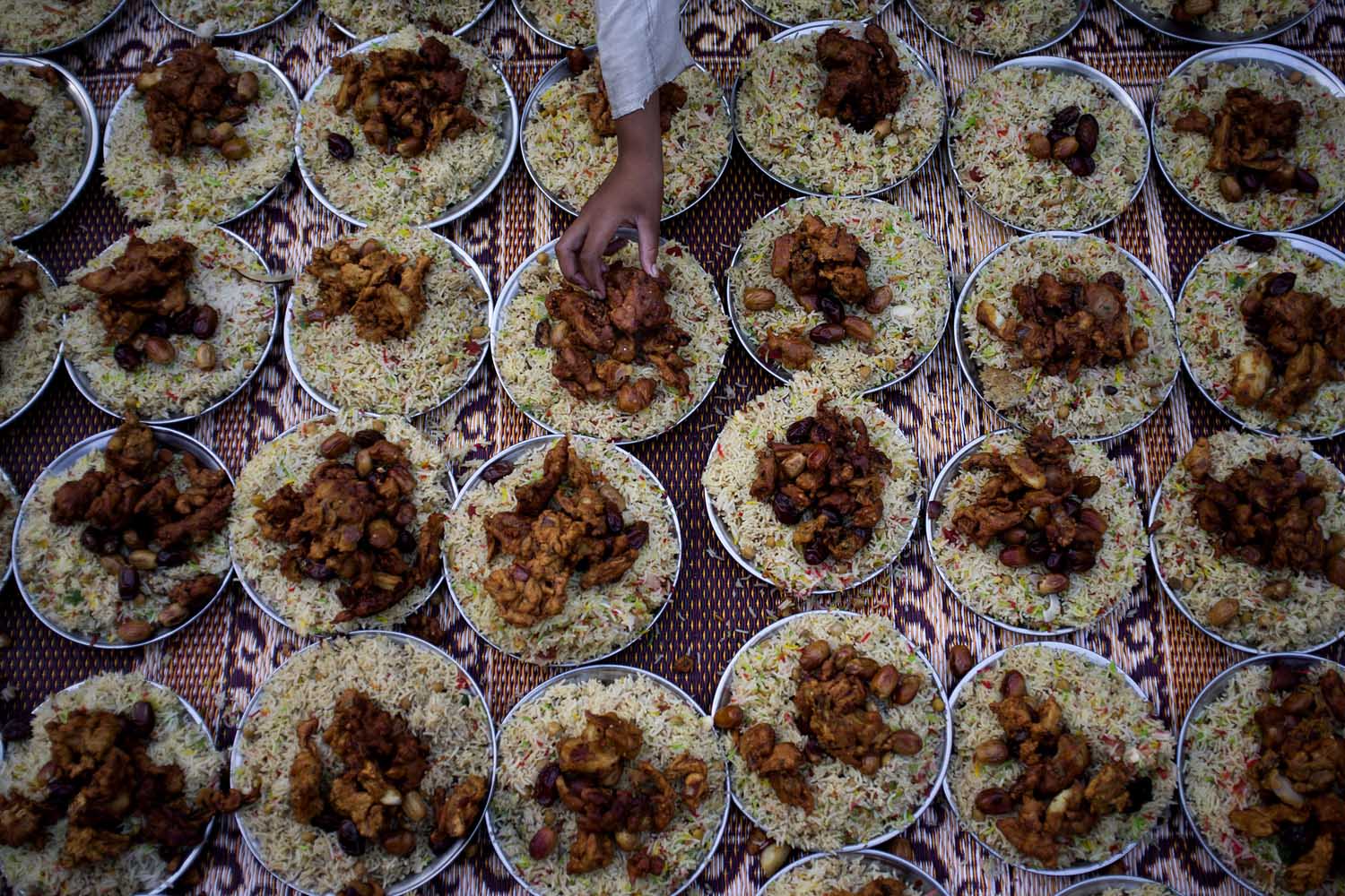 July 30, 2013. A Pakistani boy arranges plates of food for Iftar, the meal that breaks the day's fast, during the holy month of Ramadan at a roadside in Islamabad.